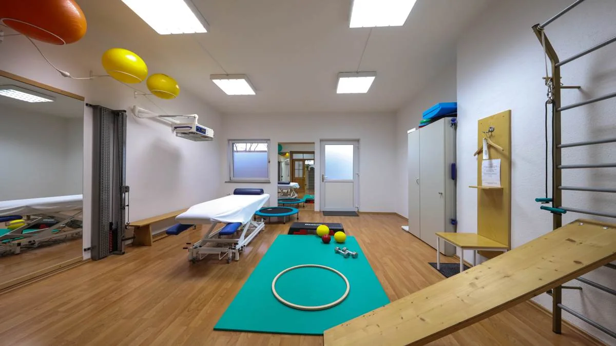 Bewegungsraum der Praxis mit Therapieliege, Sprossenwand und Trainingsmatte